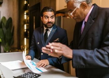 A small NYC business owner reviews mid-year finances at a counter, applying an NYC business strategy to manage rising costs.