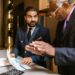 A small NYC business owner reviews mid-year finances at a counter, applying an NYC business strategy to manage rising costs.