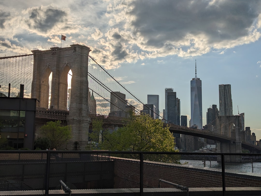 A couple sitting close together at golden hour on a rooftop bar in NYC with the Brooklyn Bridge visible in the background