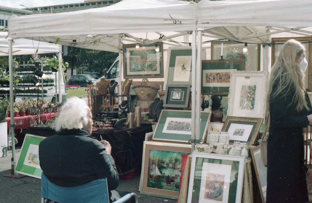 A shopper browses original artwork at a busy street fair on a New York City sidewalk