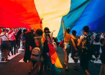 Thousands of people lining Fifth Avenue to watch the NYC Pride march, waving rainbow flags in Manhattan