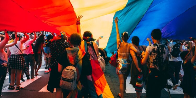 Thousands of people lining Fifth Avenue to watch the NYC Pride march, waving rainbow flags in Manhattan