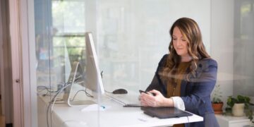 A woman entrepreneur reviews small business license documents at her New York City office desk