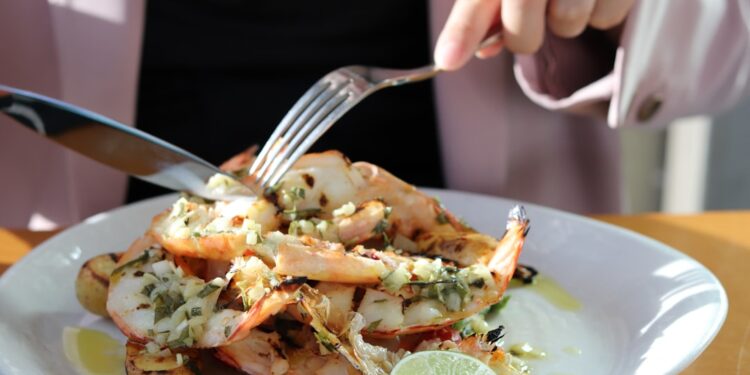 woman-eating-lobster-unsplash - NYCwebzine A woman enjoys fresh lobster rolls at a waterfront restaurant in New York City on a sunny June afternoon.