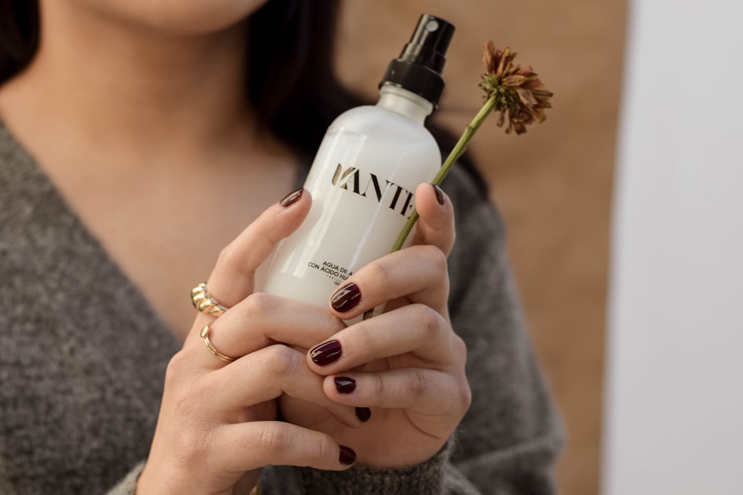 Una mujer rociando su rostro con spray fijador para sellar su maquillaje de verano contra la humedad