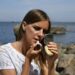 woman-in-makeup-application-mirror-unsplash - NYCwebzine Eine Frau trägt Primer auf ihr Gesicht auf, um sich auf eine Sommer-Make-up-Routine in New York City vorzubereiten