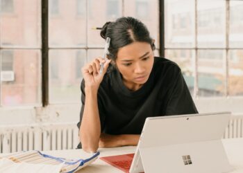 Eine Frau überprüft Genossenschaftskaufdokumente an einem Küchentisch in Brooklyn und vergleicht monatliche Kosten einer Brooklyn-Genossenschaft.