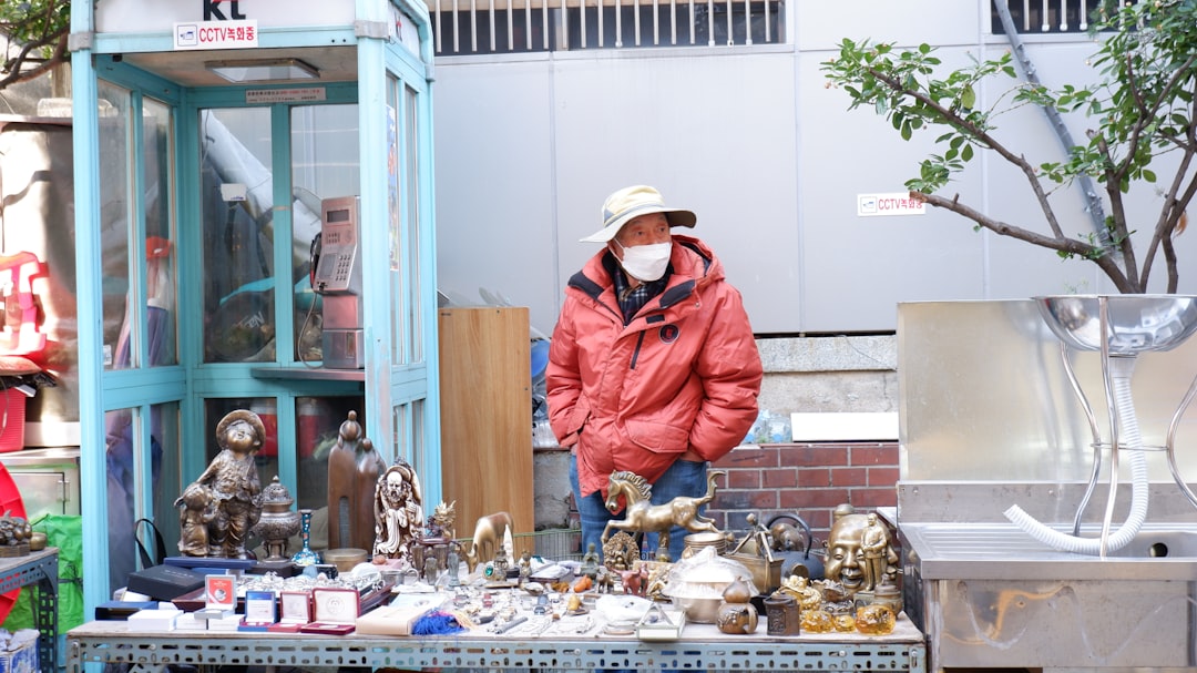 A vendor arranges her display at a street fair, with framed prints stacked against a white tent