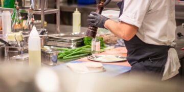 A chef carefully plates an elegant course at a Manhattan restaurant during restaurant week NYC, showcasing culinary craft.