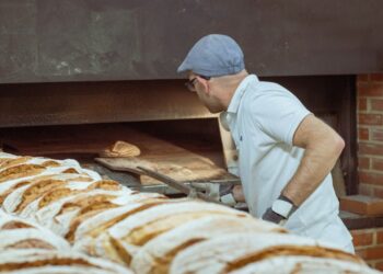 A baker hands a gluten-free loaf to a customer inside a Manhattan bakery, showing the growing demand for gluten-free.