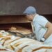 bakery-owner-serving-gluten-free-bread-unsplash - NYCwebzine A baker hands a gluten-free loaf to a customer inside a Manhattan bakery, showing the growing demand for gluten-free.