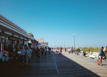 A woman walks along a sunny Jersey Shore boardwalk on a summer weekend trip from New York City