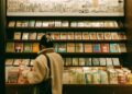 child-reading-bookstore-shelf-unsplash - NYCwebzine A young child browsing picture books at one of the best children's bookstores in NYC, surrounded by colorful shelves.