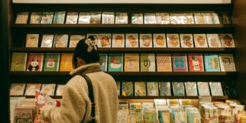 child-reading-bookstore-shelf-unsplash - NYCwebzine A young child browsing picture books at one of the best children's bookstores in NYC, surrounded by colorful shelves.