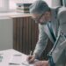 entrepreneur-signing-office-lease-unsplash - NYCwebzine A first-time business owner reviewing a commercial lease agreement at a desk in a New York City office