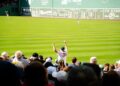 fan-cheering-baseball-stadium-crowd-unsplash - NYCwebzine A smiling fan cheering in the upper deck while watching a baseball tickets game on a sunny summer afternoon