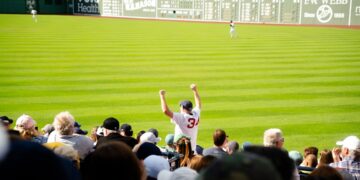 fan-cheering-baseball-stadium-crowd-unsplash - NYCwebzine A smiling fan cheering in the upper deck while watching a baseball tickets game on a sunny summer afternoon