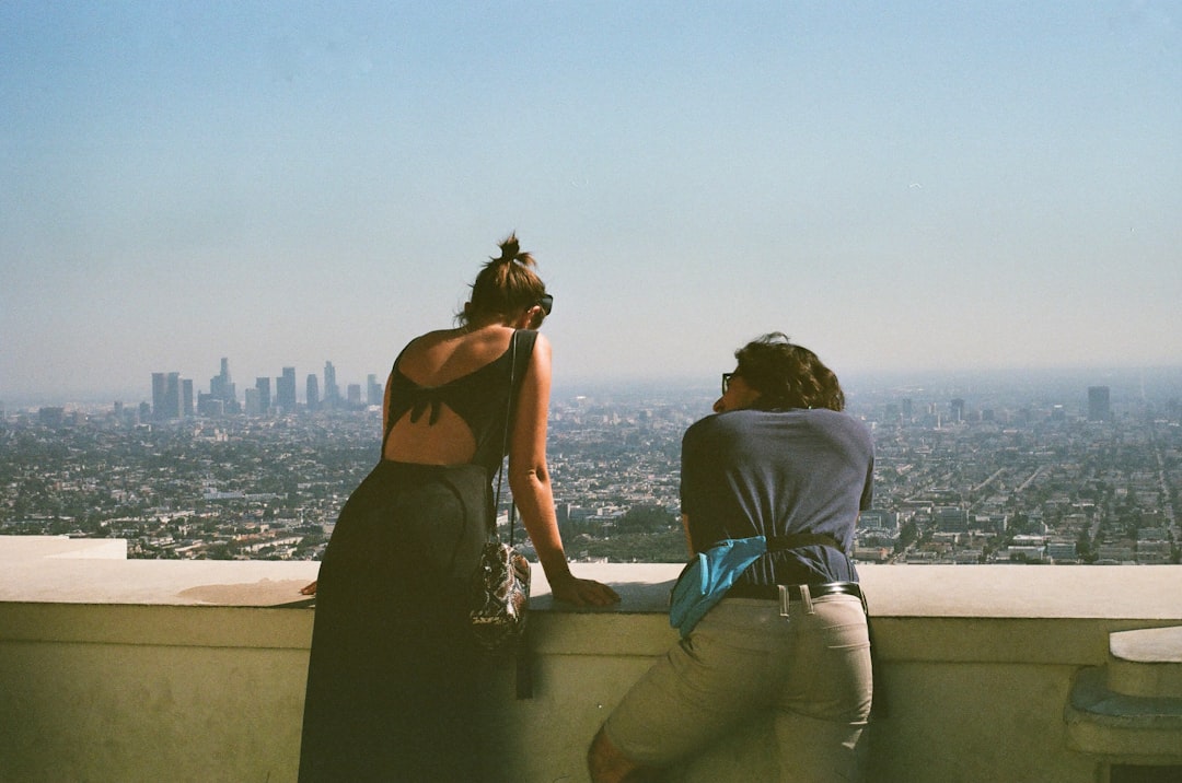 A group of friends enjoying drinks beside rooftop pools on a private terrace high above a dense urban skyline