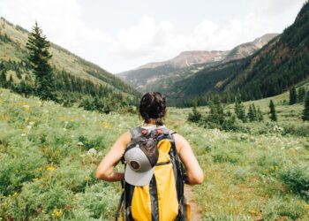 A woman pauses on a wooded trail during a Hudson Valley weekend hike, with green hills visible behind her