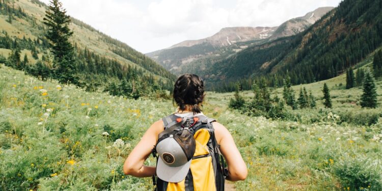 hiking-trail-woman-unsplash - NYCwebzine A woman pauses on a wooded trail during a Hudson Valley weekend hike, with green hills visible behind her