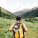 A woman pauses on a wooded trail during a Hudson Valley weekend hike, with green hills visible behind her