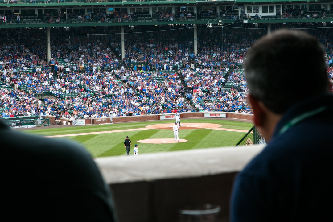 A man relaxing in his seat at stadium holding his baseball tickets on a warm summer evening