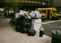 overflowing-trash-bags-on-nyc-unsplash - NYCwebzine overflowing garbage bags and cardboard boxes piled on New York City sidewalk at night beside a fire hydrant.