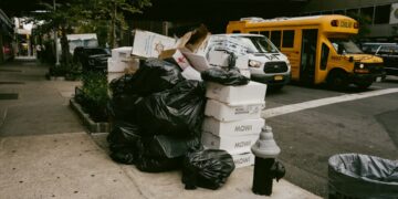 overflowing-trash-bags-on-nyc-unsplash - NYCwebzine overflowing garbage bags and cardboard boxes piled on New York City sidewalk at night beside a fire hydrant.