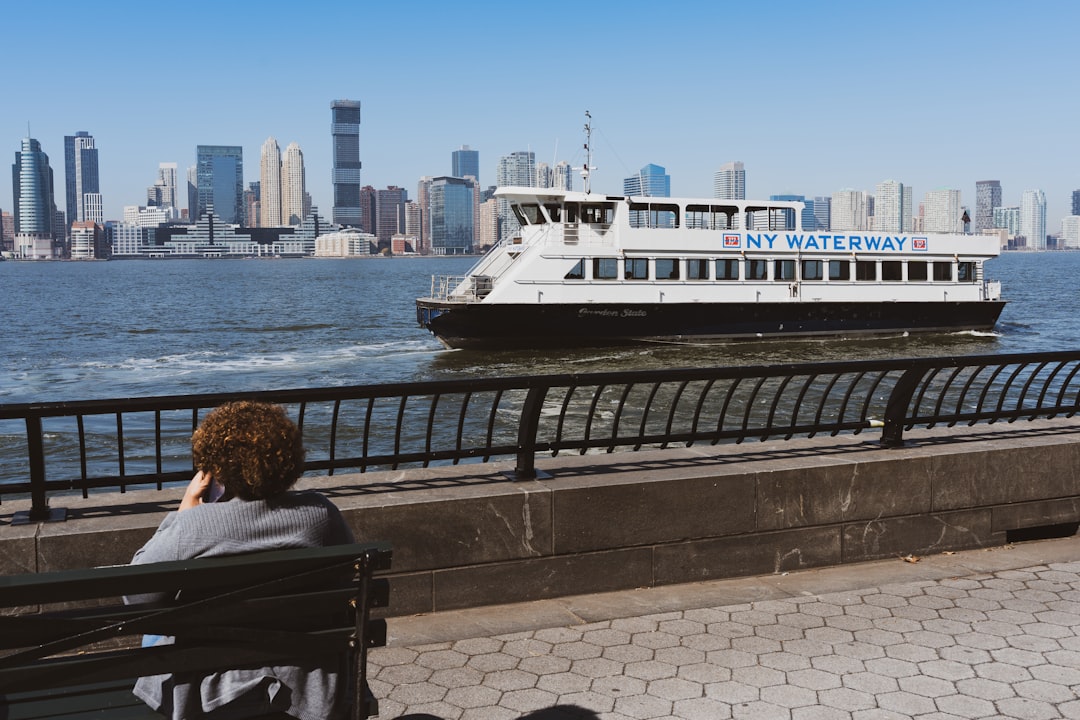 A passenger stands on the deck of an NYC ferry at sunset, enjoying the waterfront transit that makes car-free living.