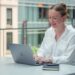 professional-woman-laptop-open-coworking-unsplash - NYCwebzine A professional woman works at a laptop inside one of New York City's best co-working spaces, with modern open-plan desks.