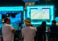 soccer-fans-cheering-big-screen-outdoor-unsplash - NYCwebzine A crowd of fans cheering at one of the FIFA World Cup fan zones on a large outdoor screen in New York City