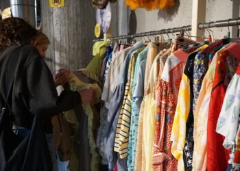 A woman carefully browsing a rack of vintage clothing at a curated secondhand store in New York City
