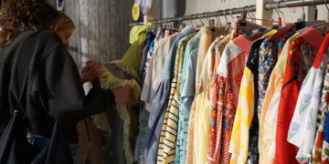 A woman carefully browsing a rack of vintage clothing at a curated secondhand store in New York City