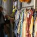 woman-browsing-vintage-clothing-rack-unsplash - NYCwebzine A woman carefully browsing a rack of vintage clothing at a curated secondhand store in New York City