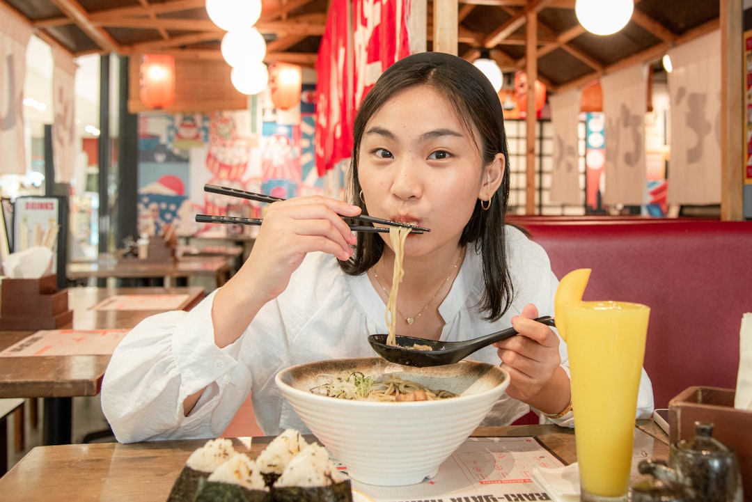 A woman enjoys rich noodles and broth at a ramen shop in New York City
