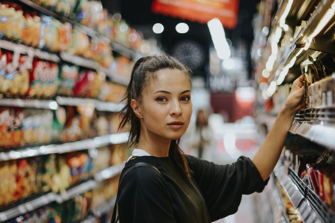 A woman selects gluten-free products from a shelf in a grocery store, illustrating the rise of gluten-free demand.