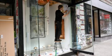 artist-in-painting-studio-new-york-unsplash - NYCwebzine A painter working at an easel in a New York studio space, representing the focused time that artist residencies provide.