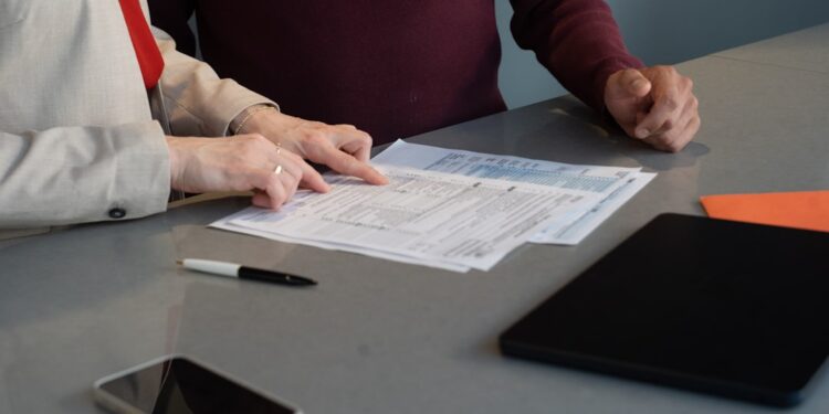 business-owner-signing-contract-desk-unsplash - NYCwebzine A small business owner reviews an employment contract before bringing on their first employee in New York City