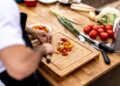chef-plating-heirloom-tomato-salad-unsplash - NYCwebzine A chef carefully plates a vibrant heirloom dish featuring August tomatoes at a New York City farm-to-table restaurant.