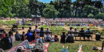 crowd-enjoying-outdoor-concert-park-unsplash - NYCwebzine A diverse crowd of people enjoying free outdoor concerts in a New York City park on a summer evening