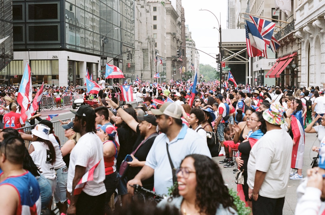 A crowd of spectators watches the India Day parade along a New York City street lined with colorful floats