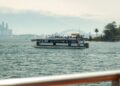ferry-deck-commute-unsplash - NYCwebzine A woman standing on the deck of an NYC Ferry vessel with the Manhattan skyline visible in the background