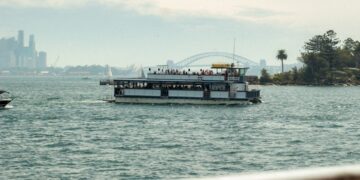 ferry-deck-commute-unsplash - NYCwebzine A woman standing on the deck of an NYC Ferry vessel with the Manhattan skyline visible in the background