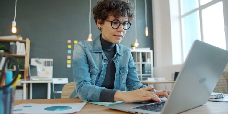freelancer-woman-working-laptop-desk-unsplash - NYCwebzine A freelancer pauses at her desk to manage burnout by stepping back from her screen and breathing