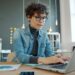freelancer-woman-working-laptop-desk-unsplash - NYCwebzine A freelancer pauses at her desk to manage burnout by stepping back from her screen and breathing