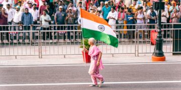 indian-woman-waving-flag-parade-unsplash - NYCwebzine A woman in traditional dress waves the Indian flag during the India Day parade on Madison Avenue in New York City