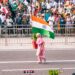 indian-woman-waving-flag-parade-unsplash - NYCwebzine A woman in traditional dress waves the Indian flag during the India Day parade on Madison Avenue in New York City