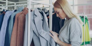 woman-browsing-sustainable-clothing-rack-unsplash - NYCwebzine A woman examines ethically made garments while building a capsule wardrobe at a New York City independent boutique