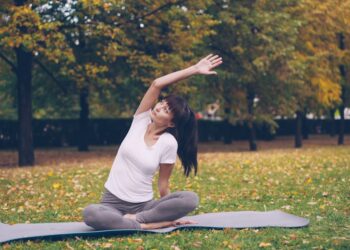 A woman practicing yoga on a mat at an outdoor fitness class in a New York City park