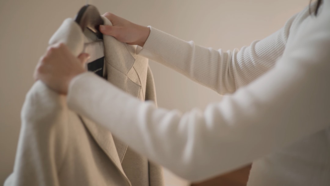 A woman carefully folds a small collection of neutral pieces representing a thoughtfully built capsule wardrobe